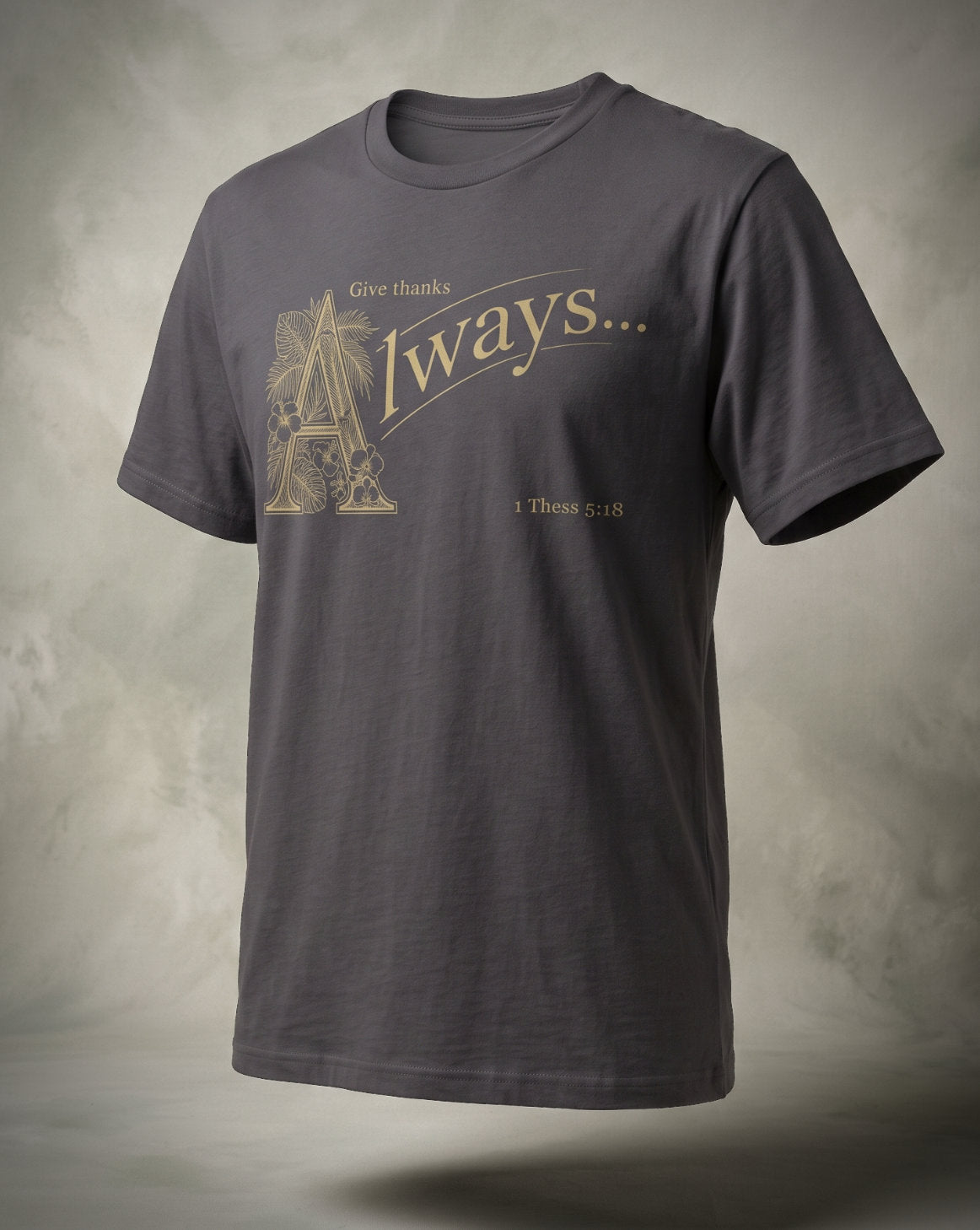 Give Thanks Always t-shirt in charcoal with gold ornamental lettering and 1 Thess 5:18, three-quarter studio view
